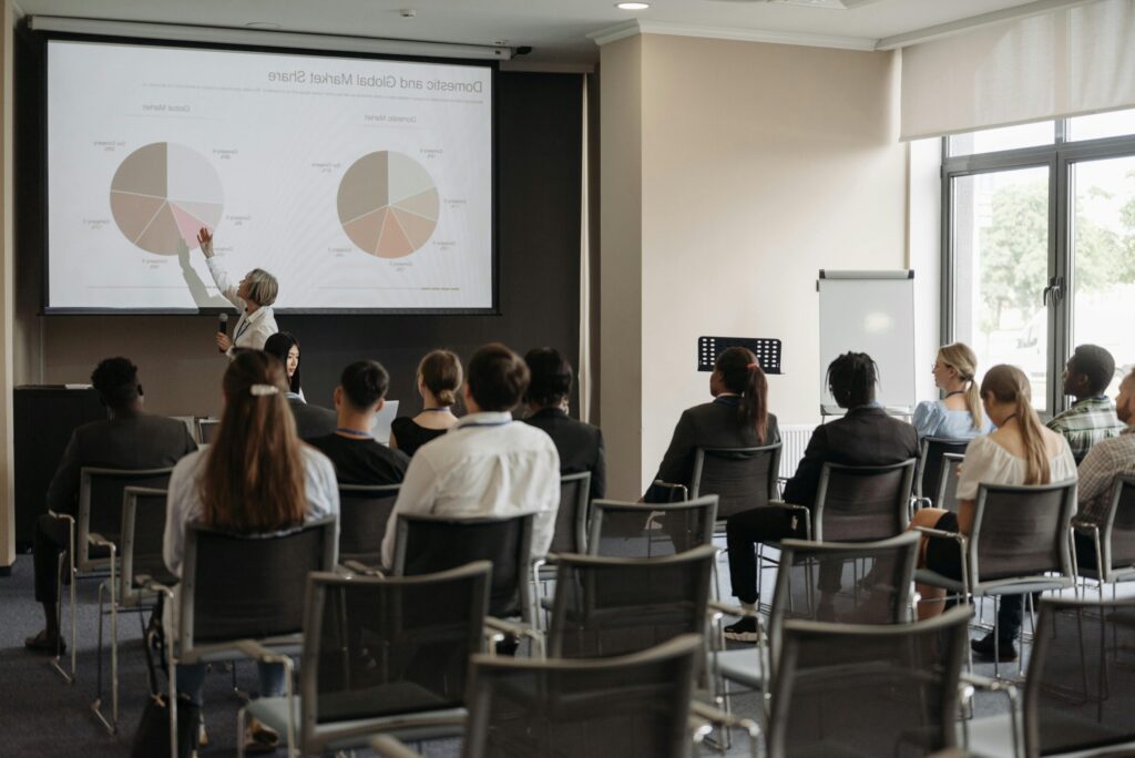 pexels photo 8761523 8761523 Business professionals attending a seminar with a presentation on market share, highlighting diverse participation.