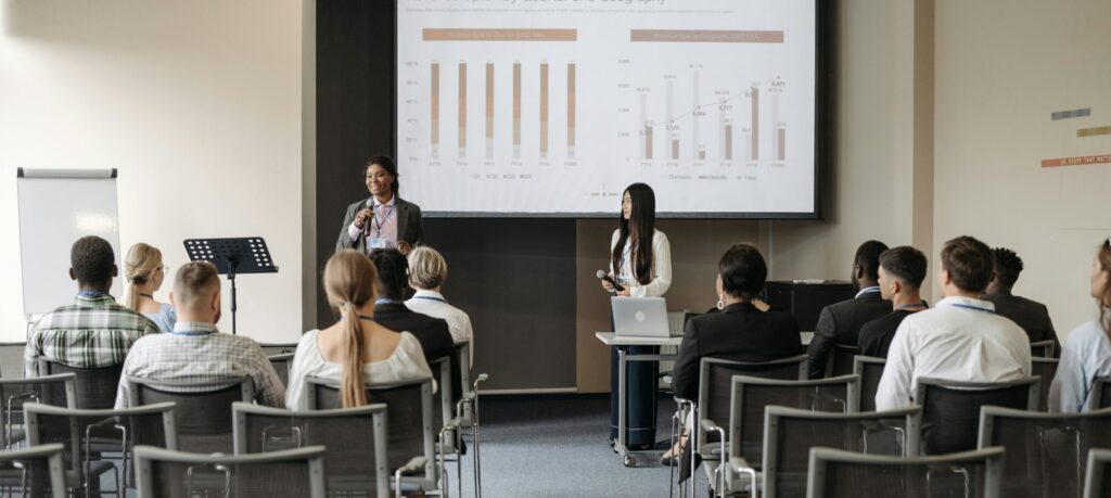 Professional business seminar with audience listening to presenters sharing data insights.
